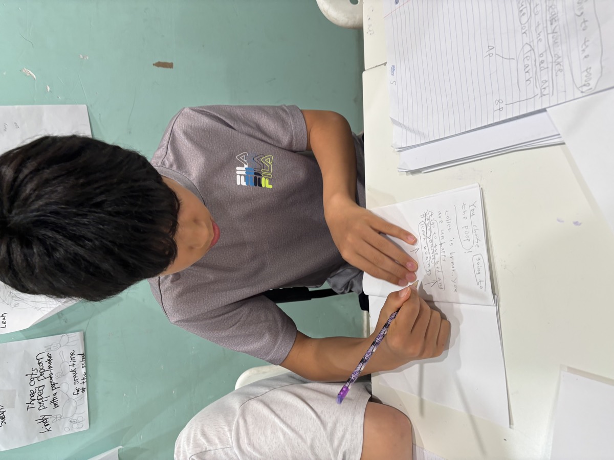 A student working through the written geography quiz in his notebook