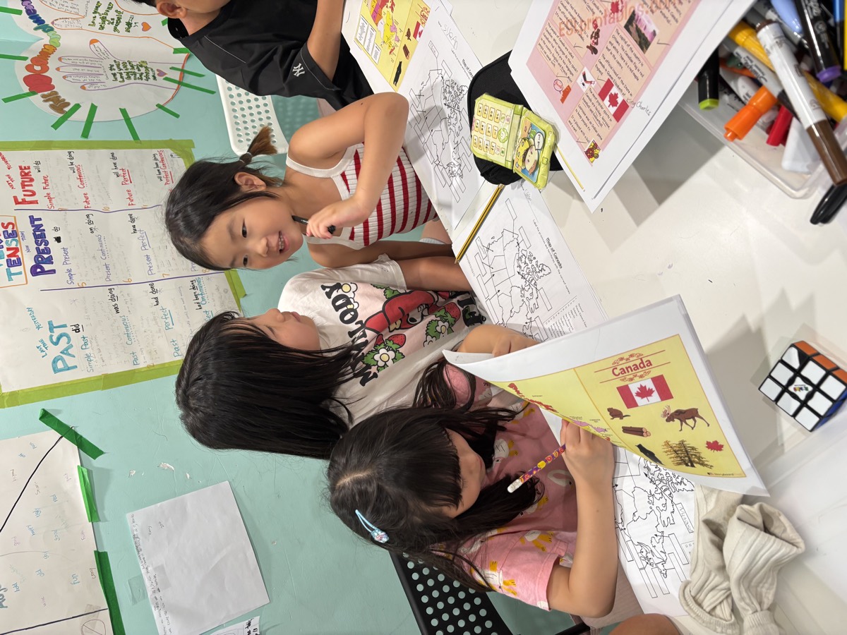 Two young students talking together over their Canada worksheets