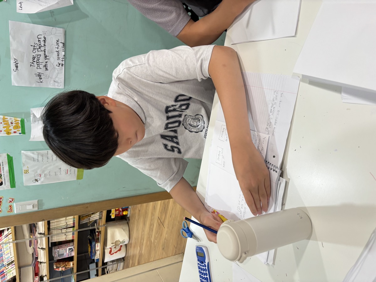 A student writing in his notebook at a classroom desk