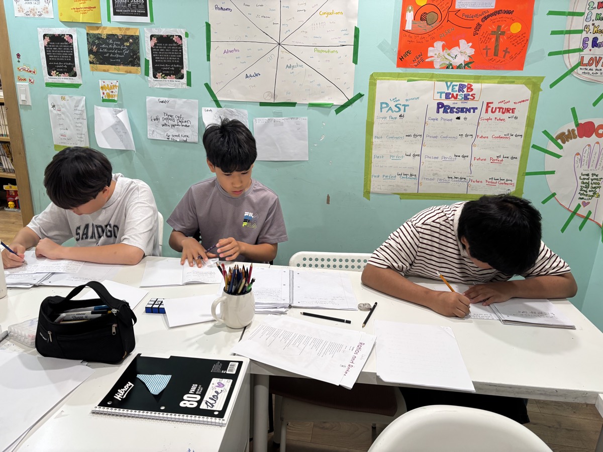 Older students working at a table finishing their writing projects