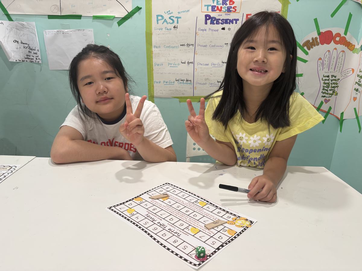 Two students smiling behind their completed math board game