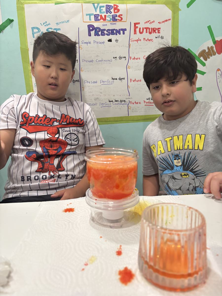 Two students holding up their orange and red lava lamp jars
