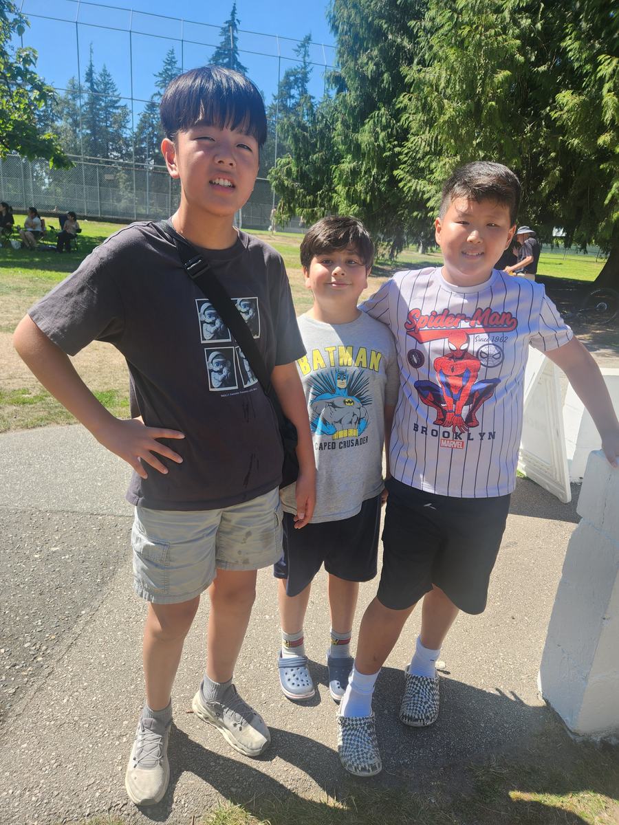 Three students standing together in the park on a sunny day