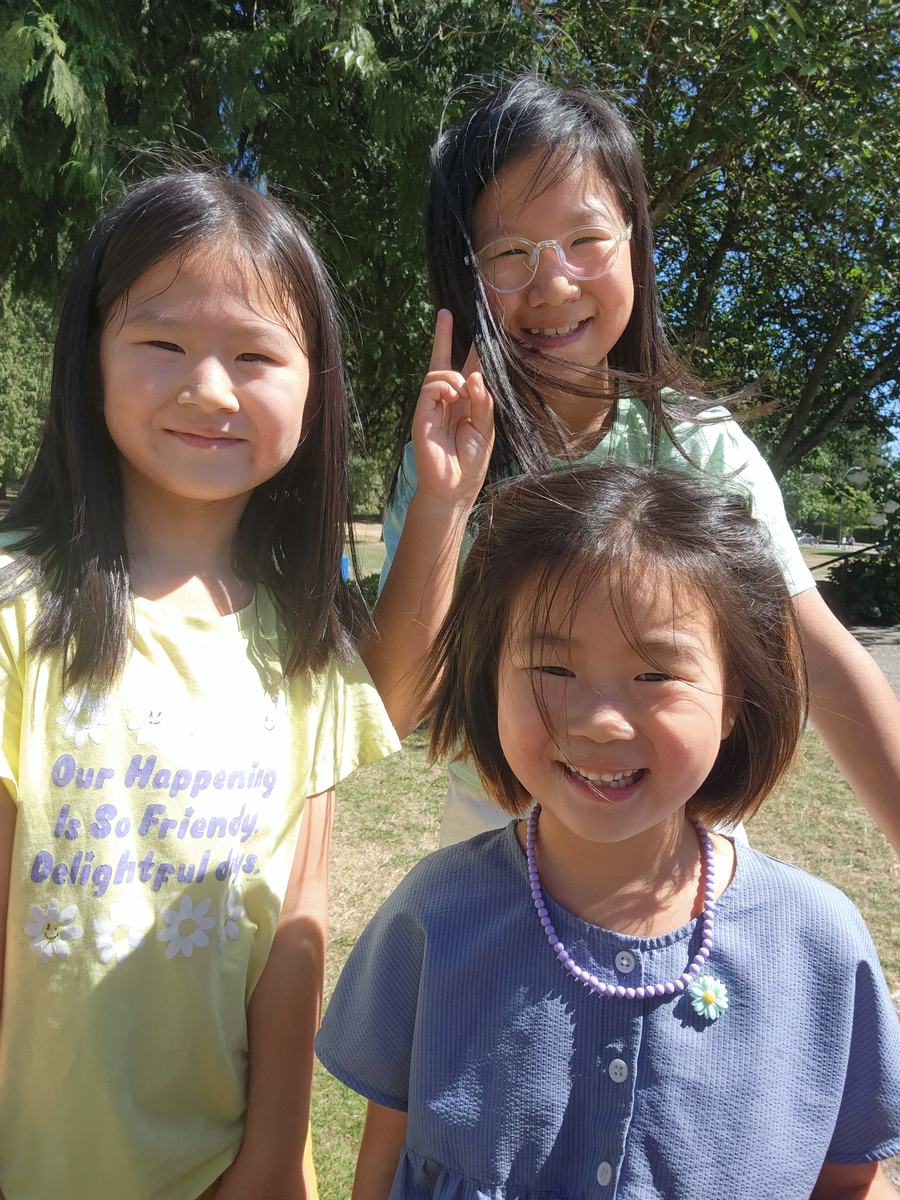 Three young students smiling at the camera outdoors