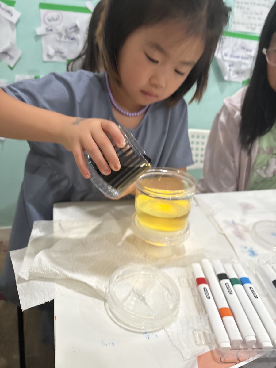 A student carefully pouring liquid into a jar of yellow oil