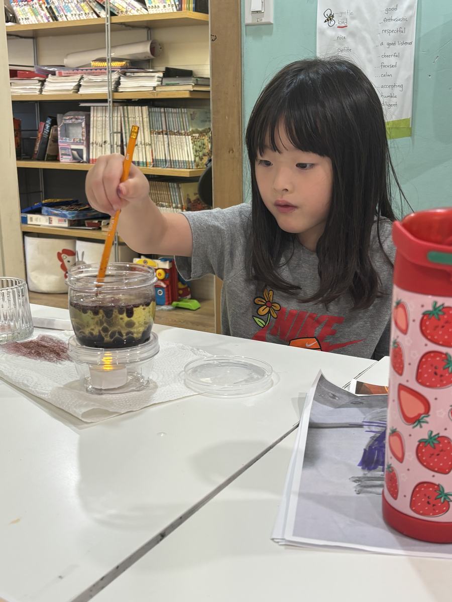 A student stirring her lava lamp jar with a pencil
