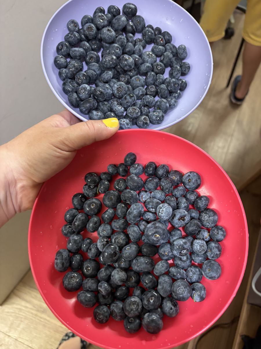 Two bowls piled with fresh blueberries held up to the camera