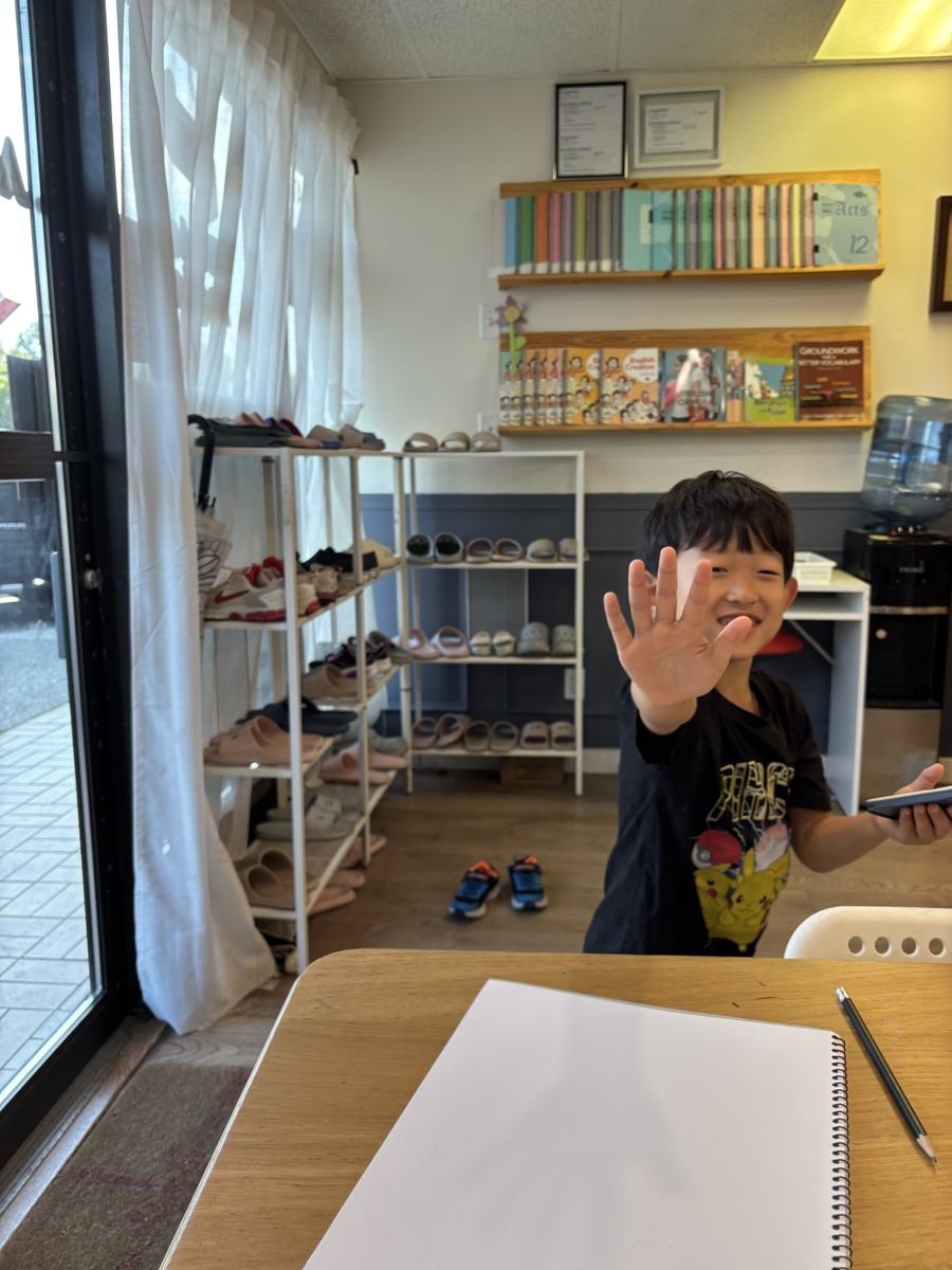 A student waving at the camera from the brainstorming table