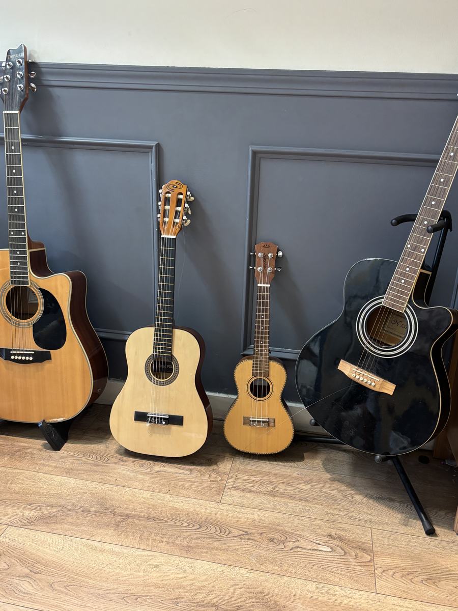 Four guitars and a ukulele lined up against the wall