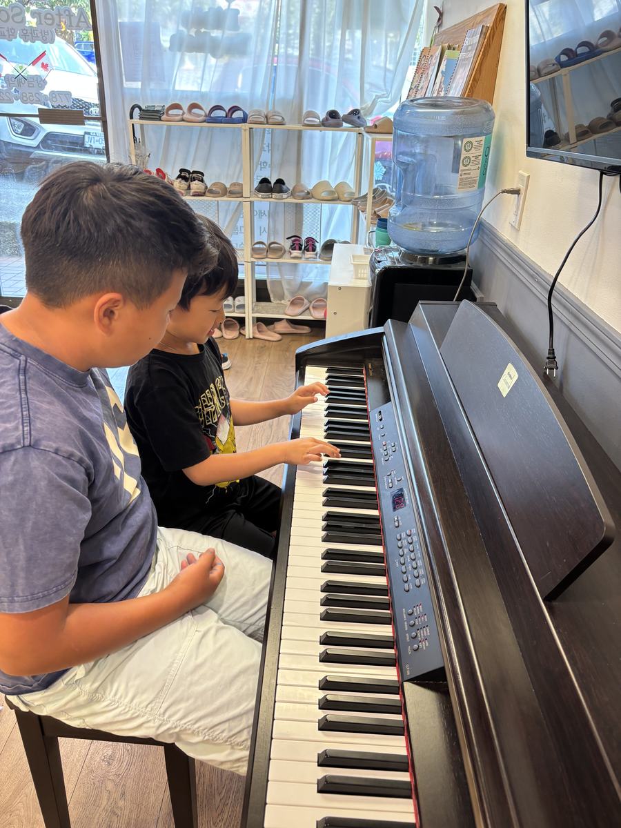 Two students sitting at the piano playing together