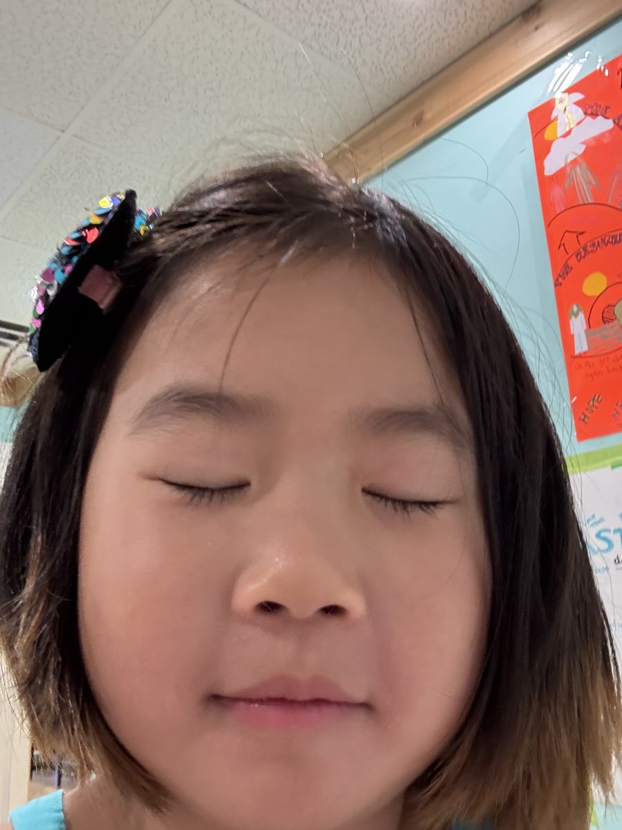 A young student smiling at the camera in the classroom