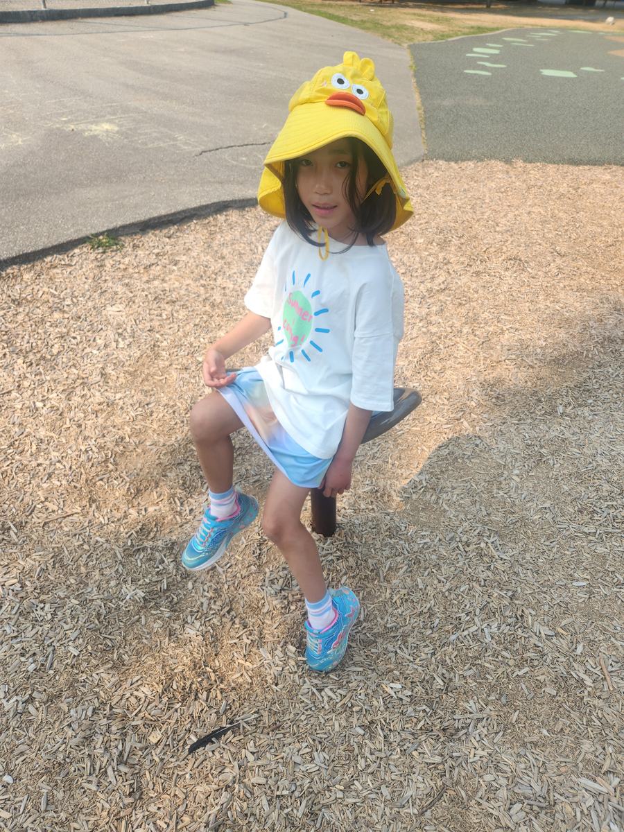 A young student in a bright yellow sun hat smiling outdoors