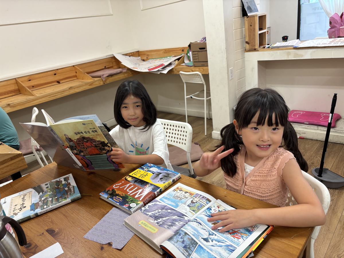 Two students at the table surrounded by open magazines and books, looking for material