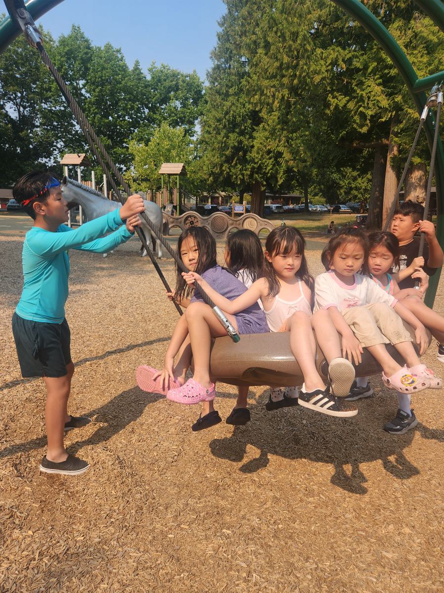 Students crowded onto the big basket swing at the playground