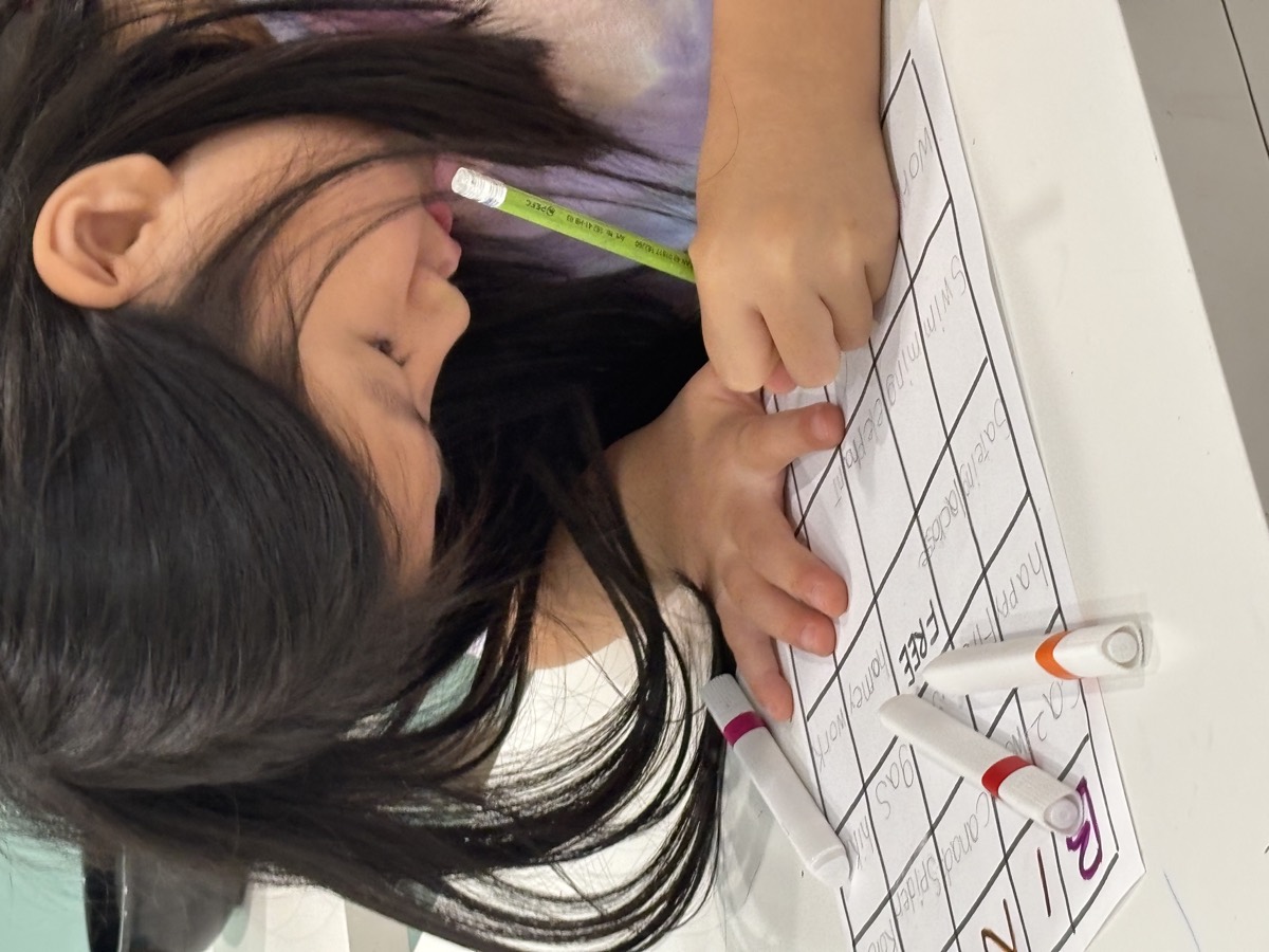 A young girl concentrating as she writes on her worksheet