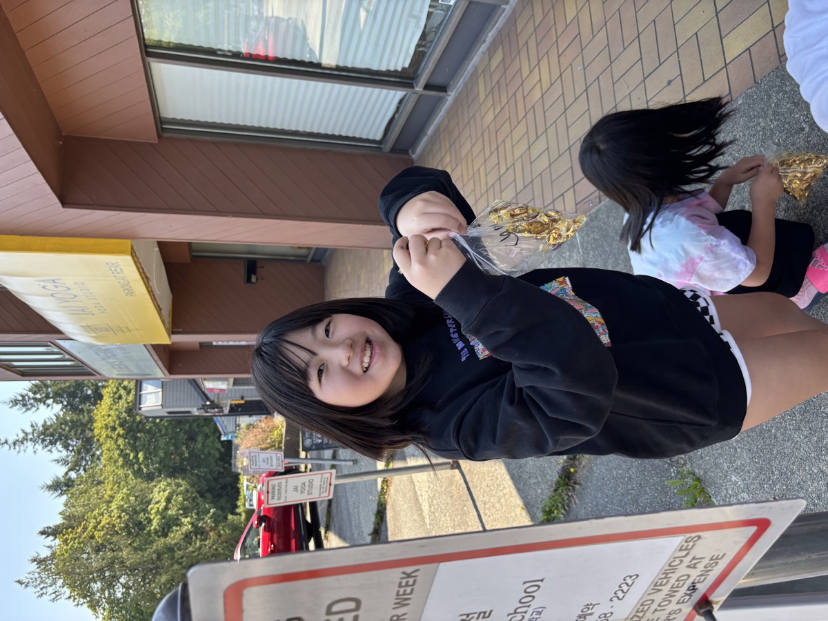 A girl smiling proudly holding her bag of golden chocolate coins