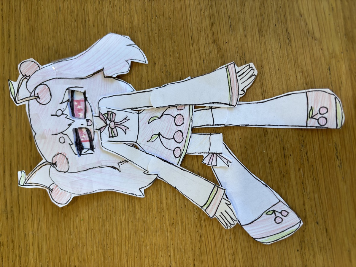 A hand-drawn and cut-out paper doll with pigtails