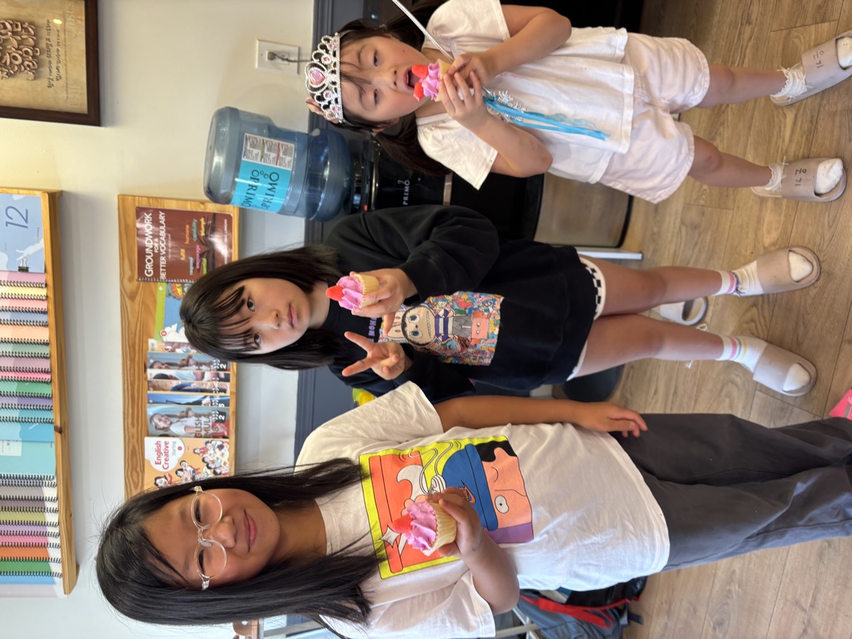 Three girls posing with their pink frosted cupcakes