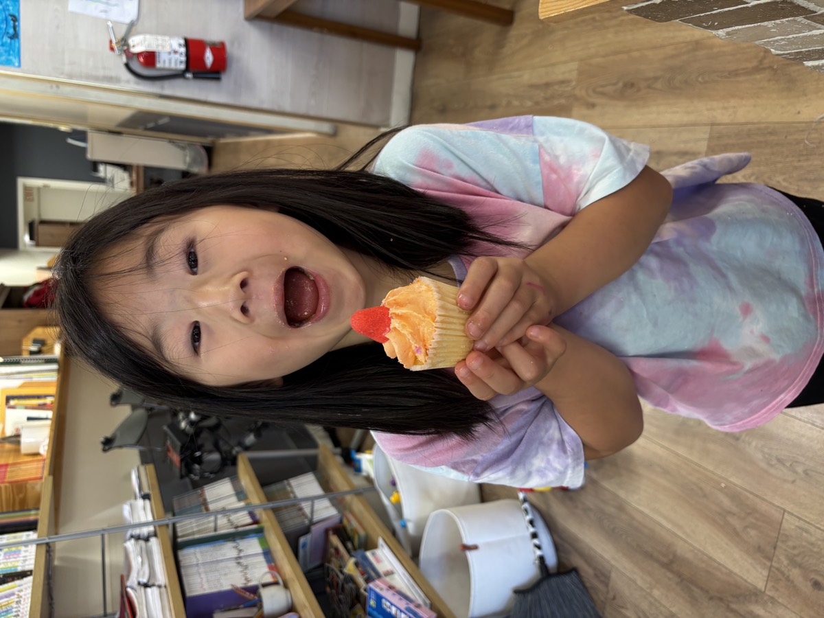 A girl with a huge excited expression holding her cupcake