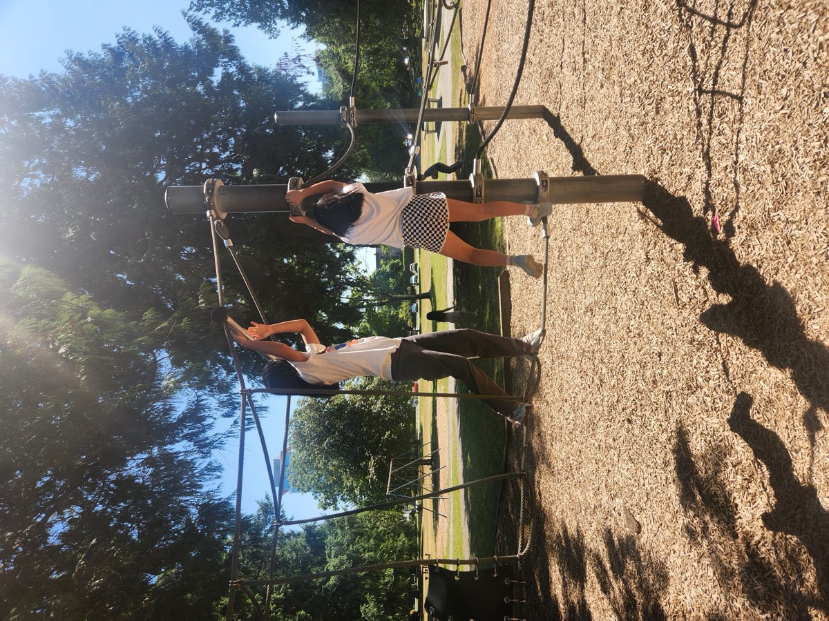 Two children climbing on the rope structure at the park playground