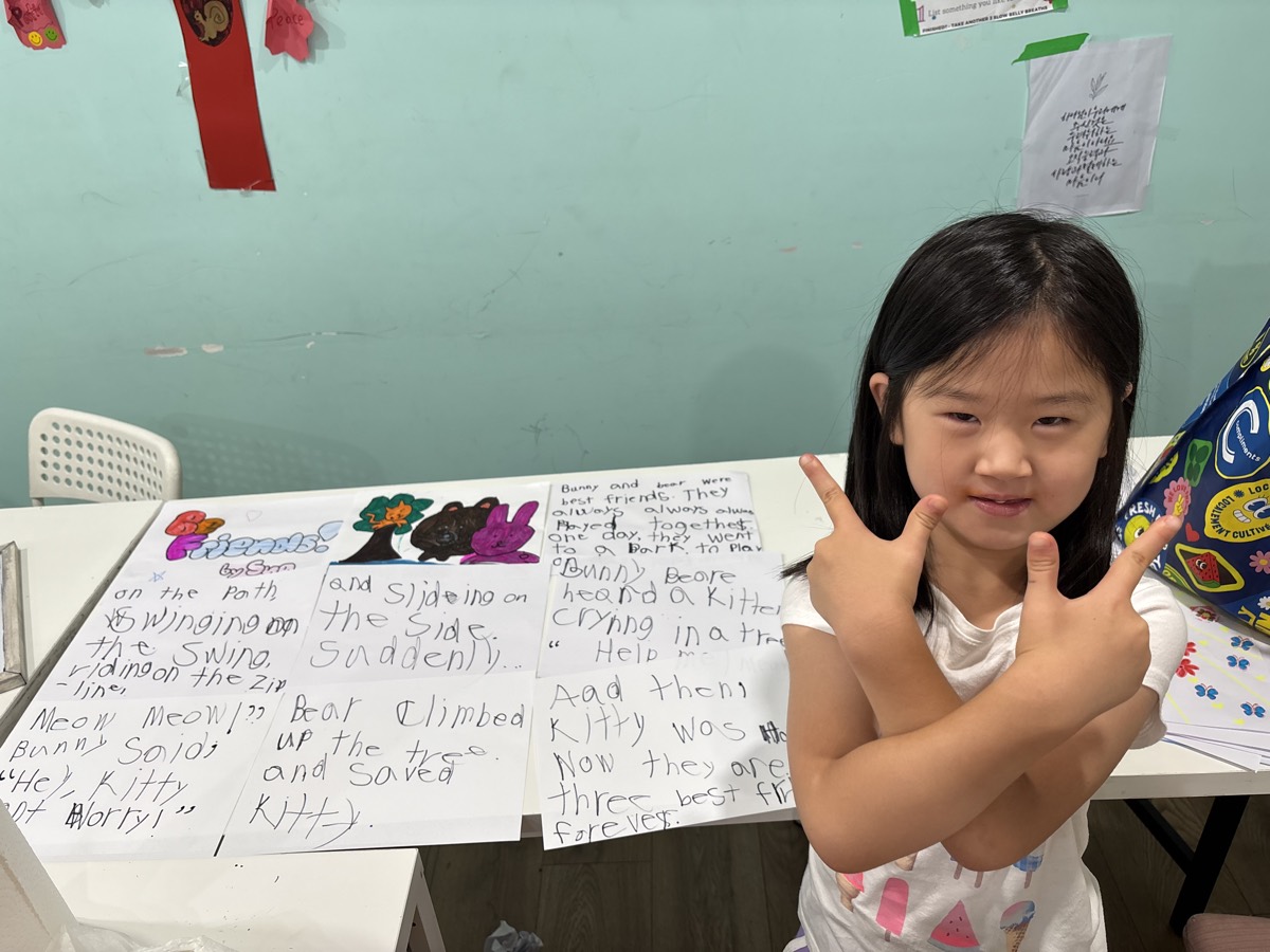 A young author posing proudly beside her finished story pages