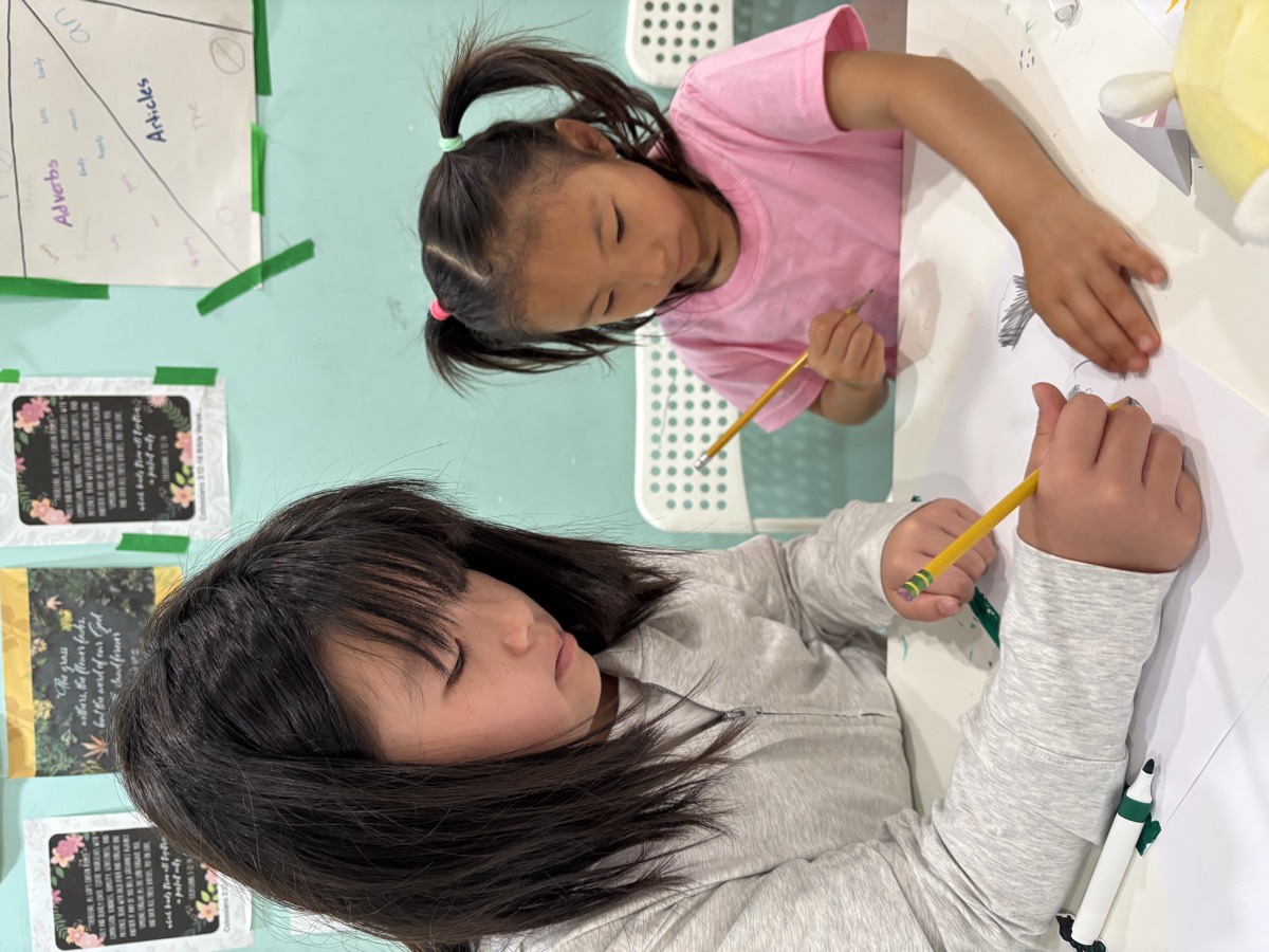 An older student helping a younger camper write her story