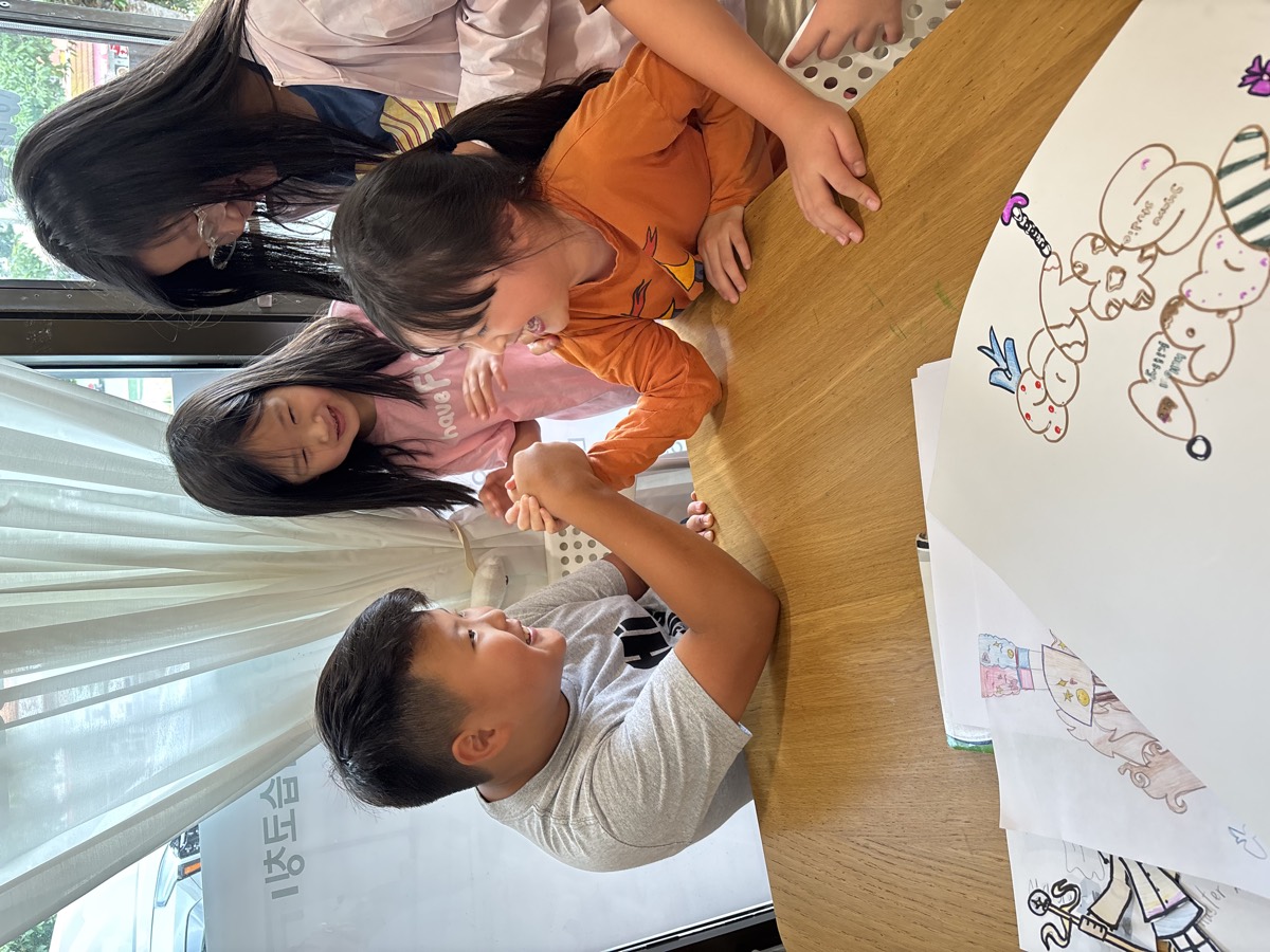 An arm-wrestling rematch with kids gathered around the table