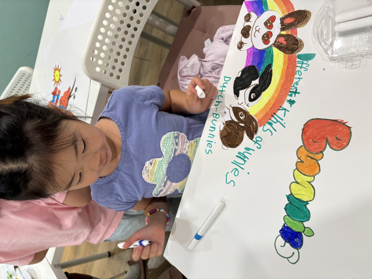 A young girl coloring her kinds-of-bunnies poster