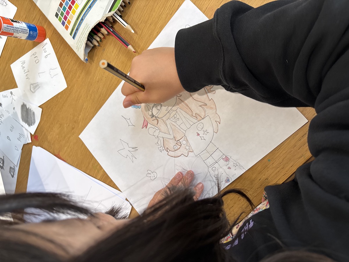 A girl drawing a detailed scene with colored pencils