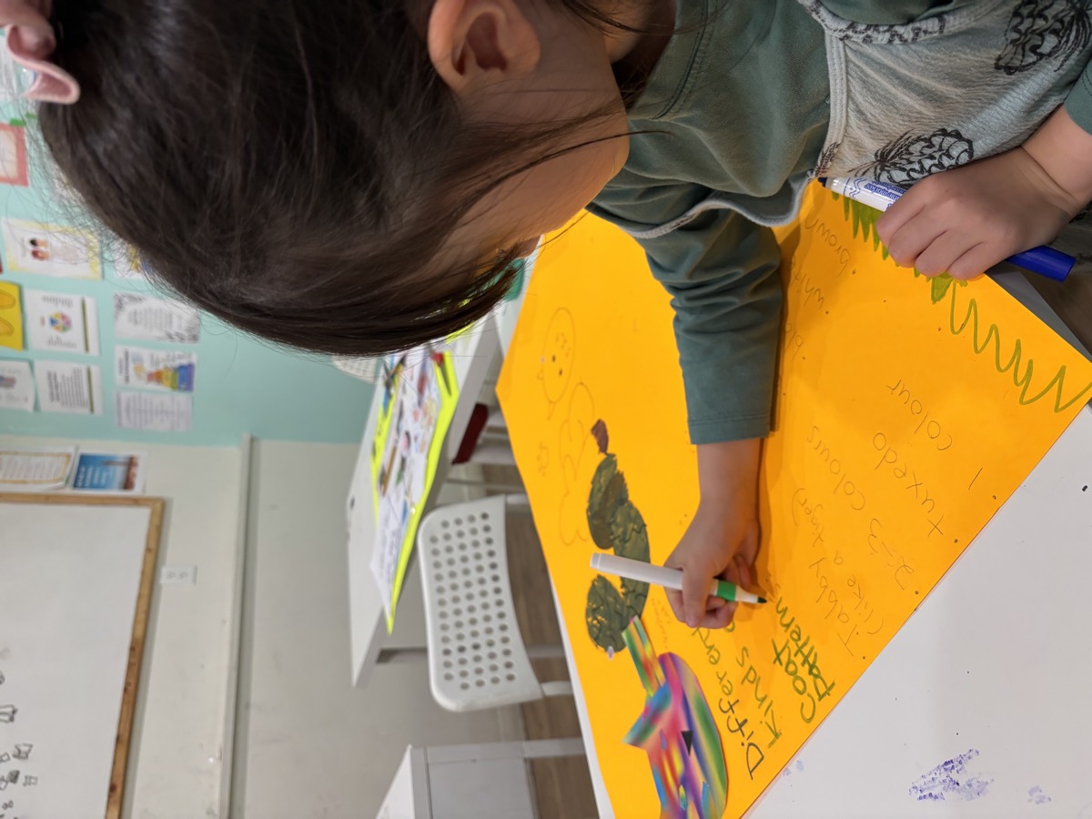 A girl working on her Different Kinds of Cats poster on orange paper