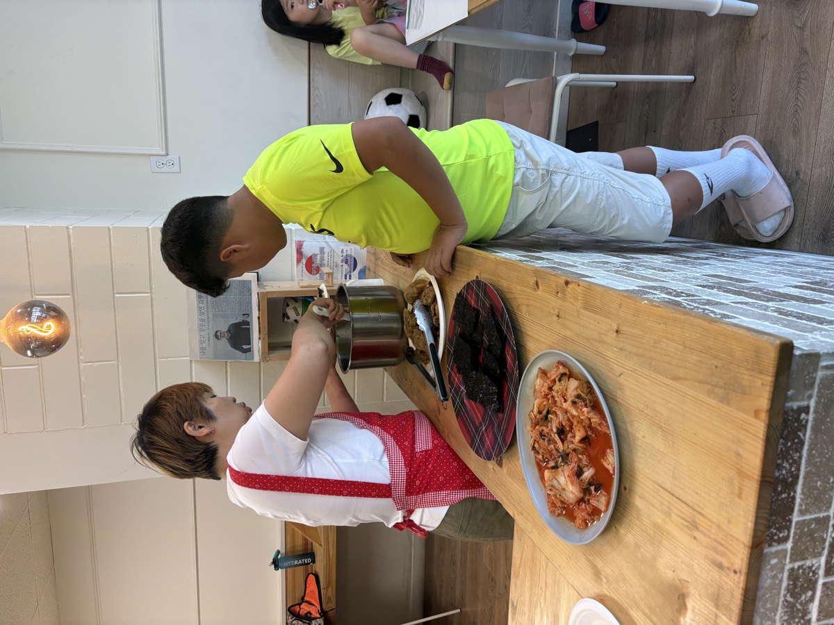 A boy getting his lunch served at the counter by the teacher