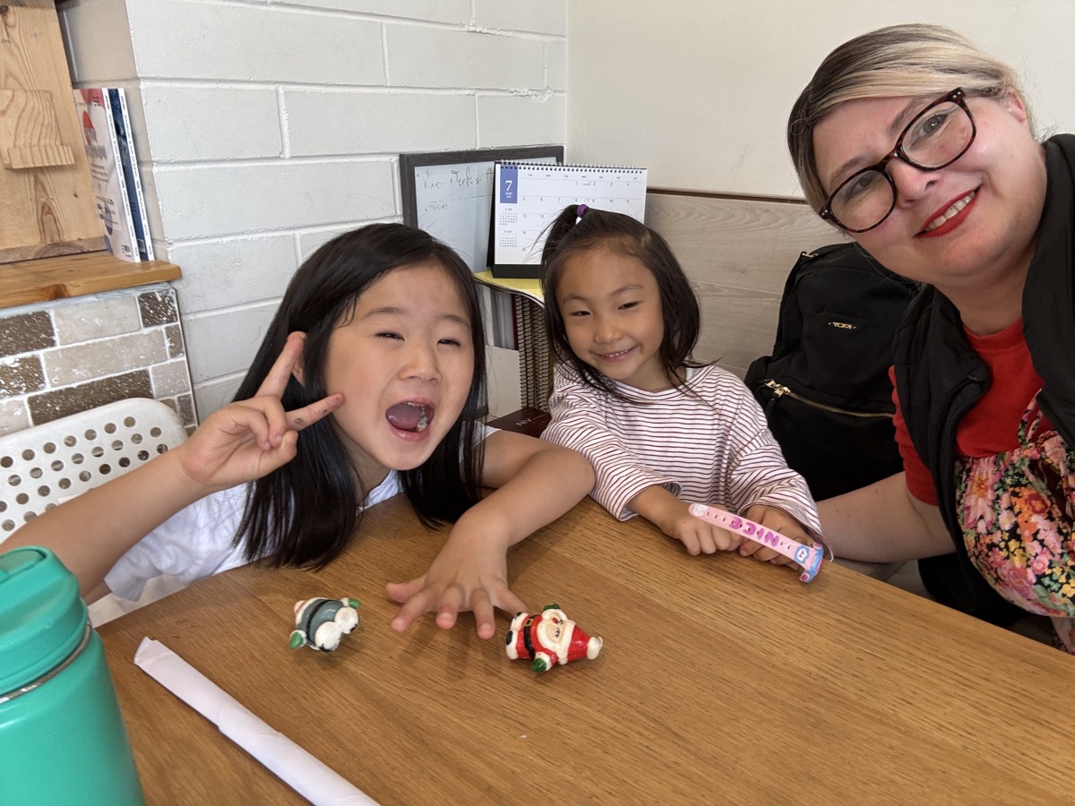 Two girls making silly faces with Ms. Diane at the table