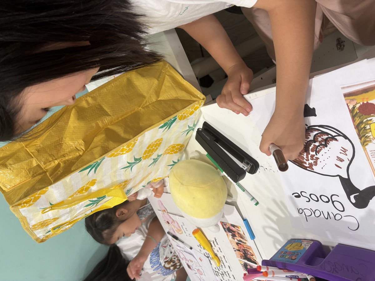 A girl lettering the Canada Goose title on her poster