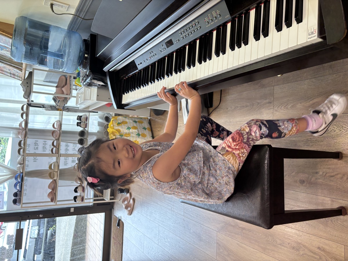 A little girl smiling on the piano bench
