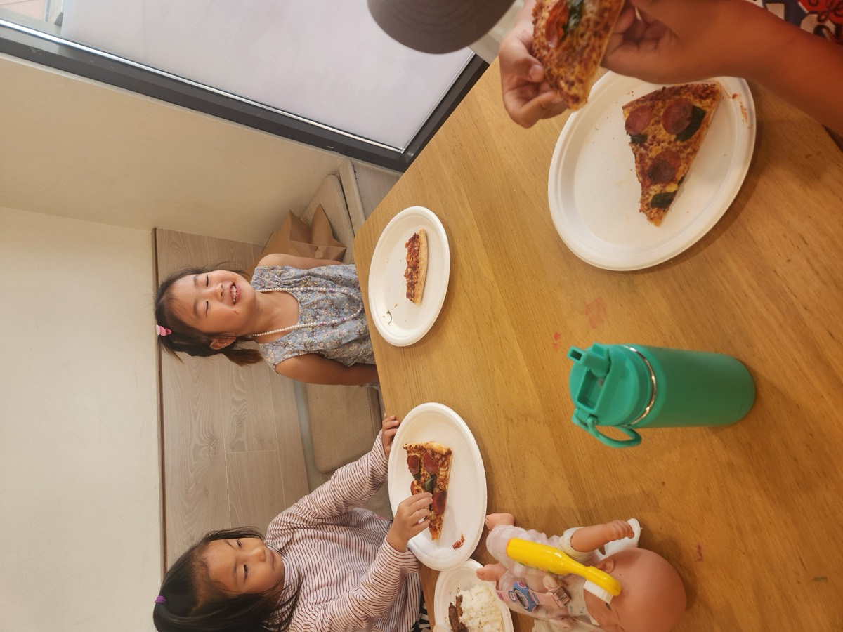 Girls giggling over their pizza slices at the table