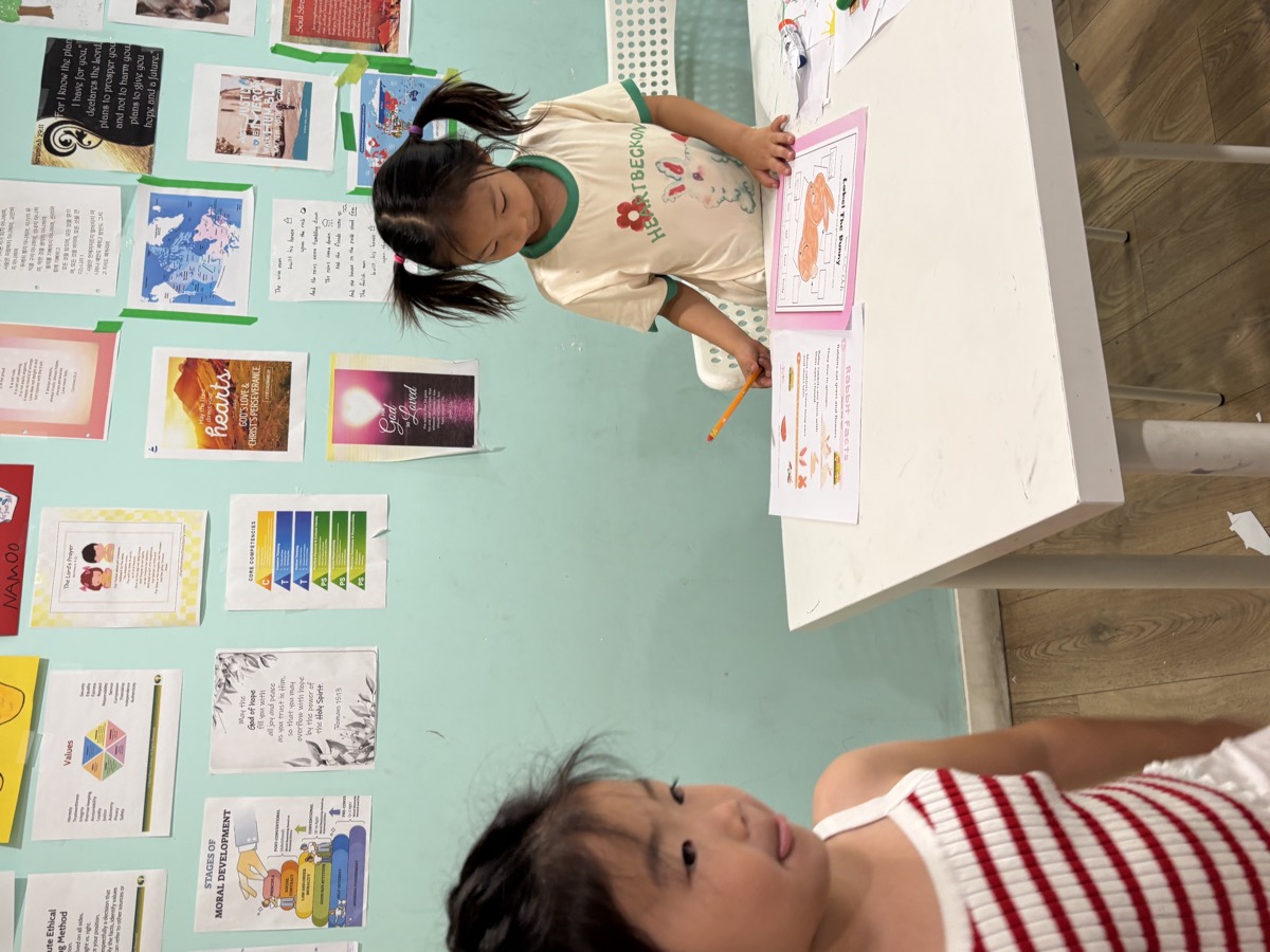 Leah standing at the desk marking her students' worksheets