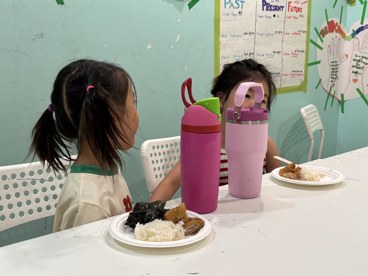 Two girls having lunch — rice, donkatsu, and seaweed on their plates