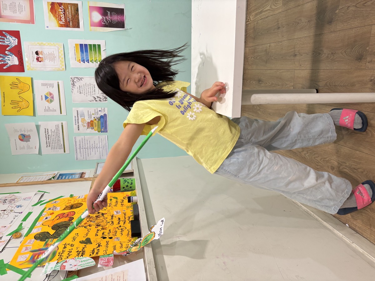 Sua beaming with confidence, pointer raised, standing at the classroom board