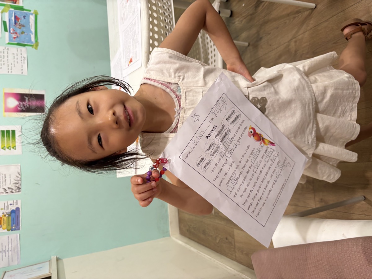 A student proudly holding up her completed Parrots worksheet