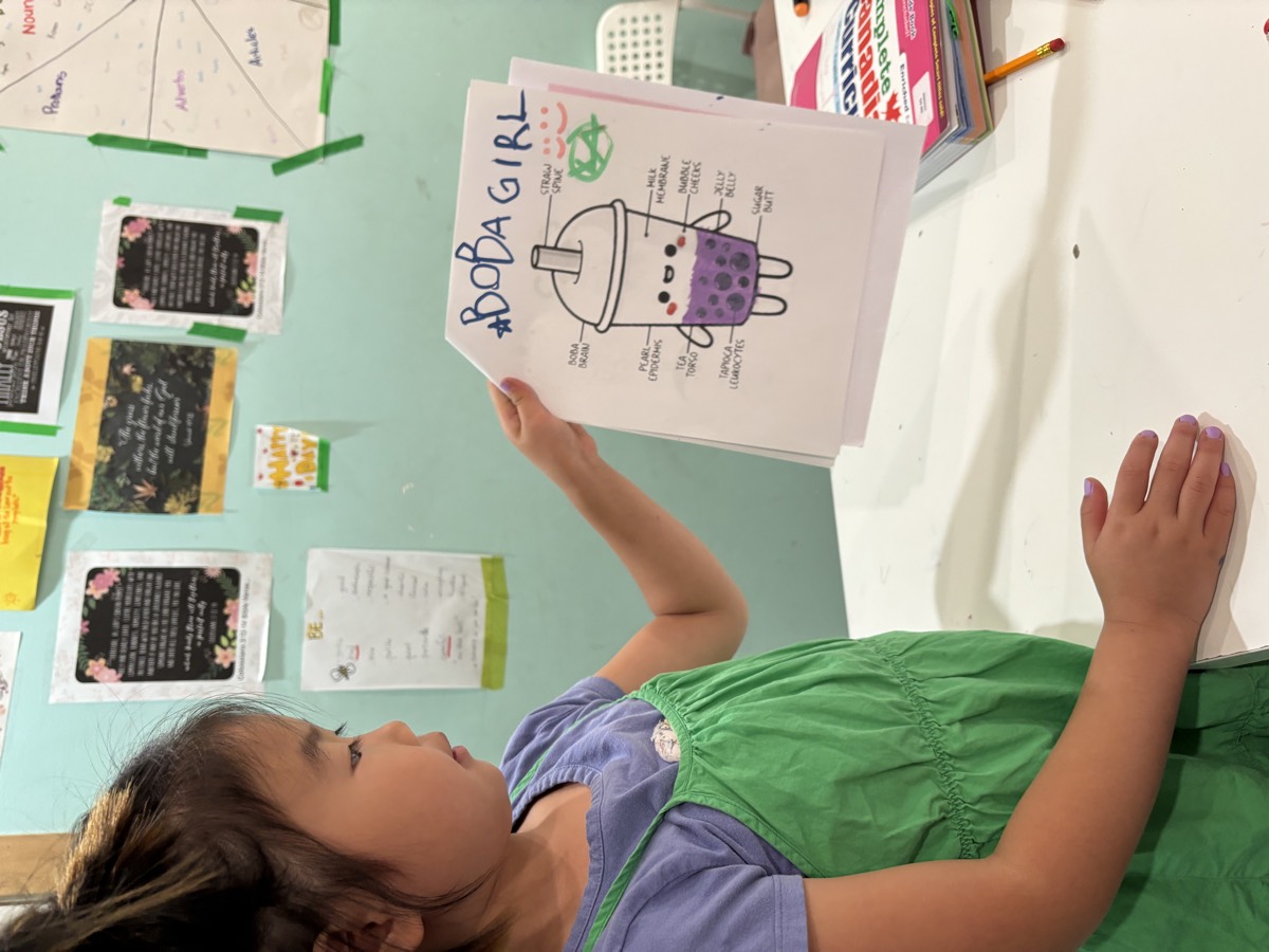 A young student holding up the hashtag Boba Girl character worksheet