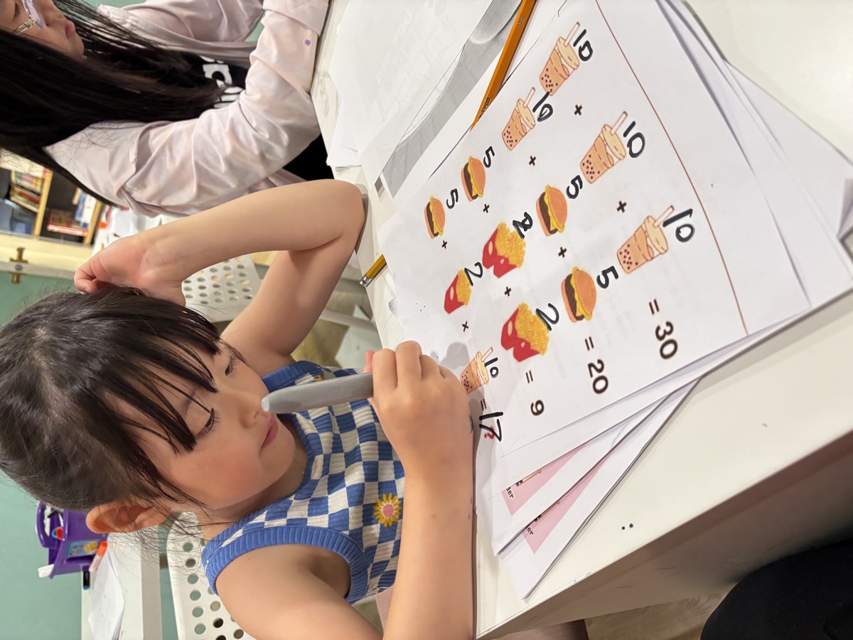 A student working through a bubble tea themed math worksheet with a marker