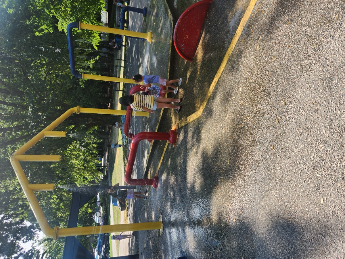 Kids playing together at the splash park water sprayers on a sunny day