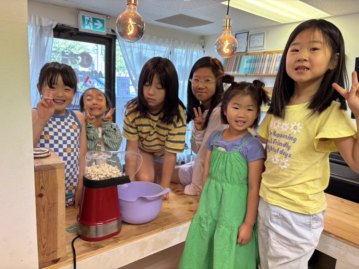 A group of girls posing with peace signs around the red popcorn maker
