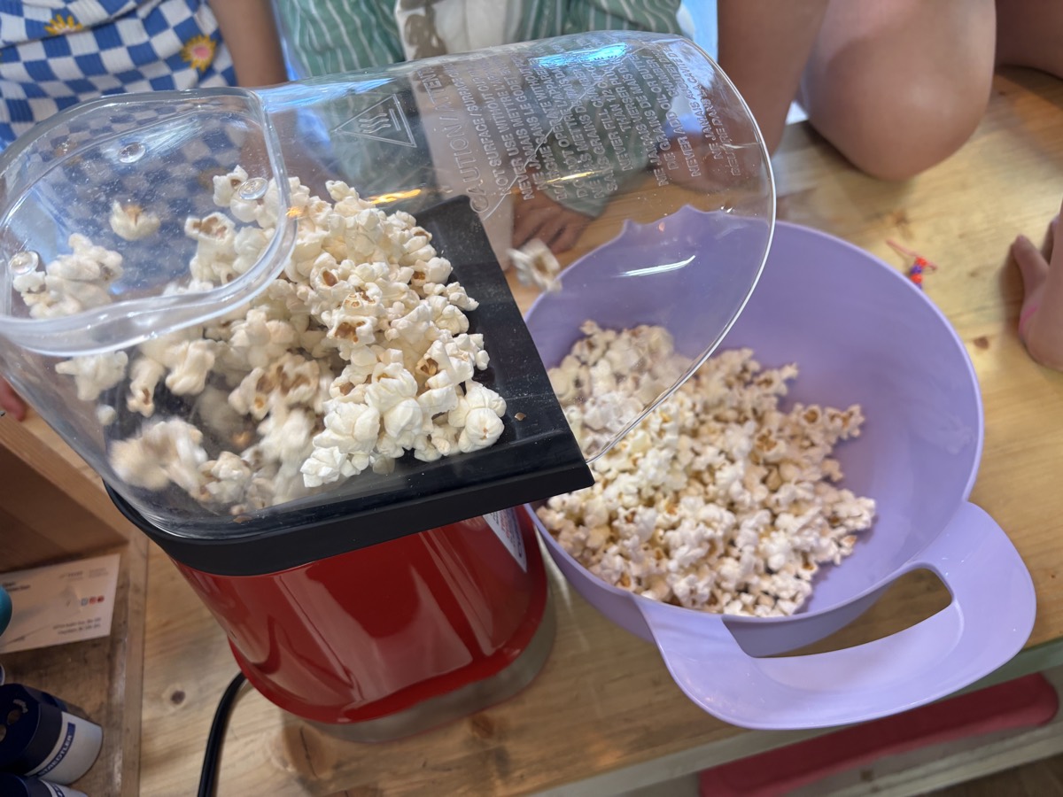 Fresh popcorn pouring from the popper into a purple bowl