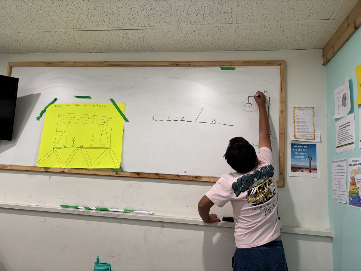 Minwoo writing a soccer ball hangman puzzle on the whiteboard
