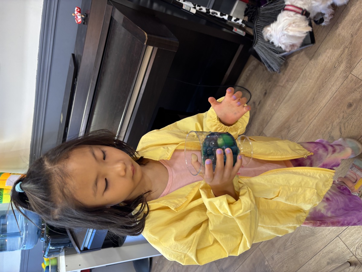 A student holding a clear cup of blue jelly filled with grapes and blueberries