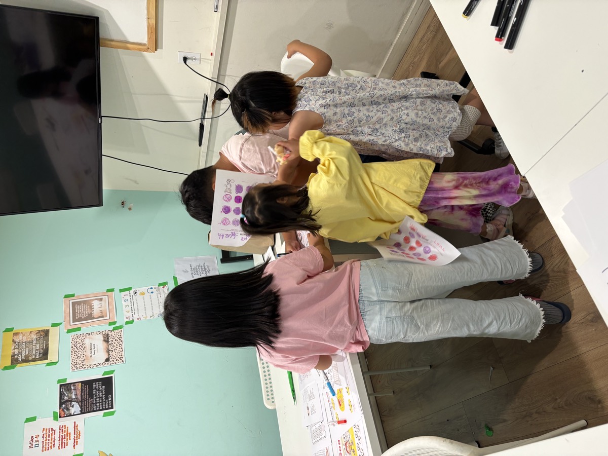 Students gathered around Mrs. Diane to have their soccer worksheets checked and marked