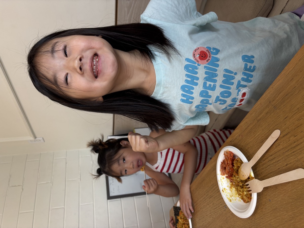A student smiling widely with a fist raised beside her cleaned plate of kimchi fried rice