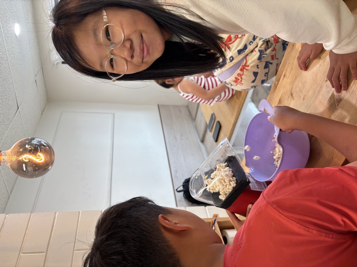Students gathered around the popcorn machine popping fresh popcorn into a purple bowl