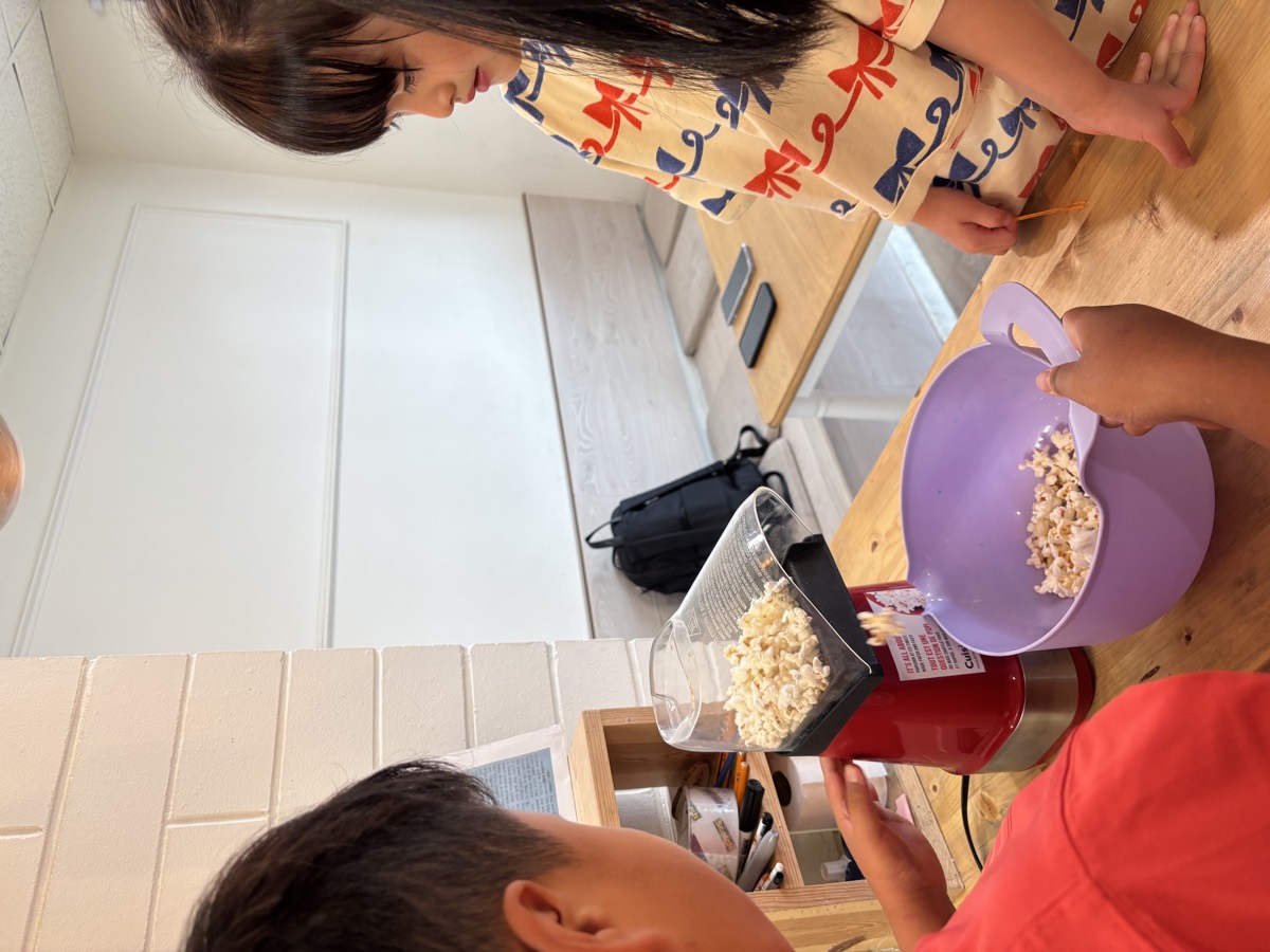 Fresh popcorn tumbling out of the machine into a big purple bowl